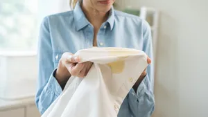 Vrouw bekijkt witte blouse met vetvlekken.