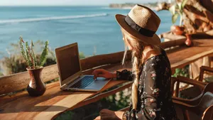 Business woman working with computer on the beach.  Freelance concept. Pretty young woman using laptop in cafe on tropical beach