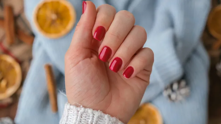 Woman manicured hands, stylish red nails, copy space. Blue sweater Closeup. Winter or autumn style of nail design concept. Beauty treatment