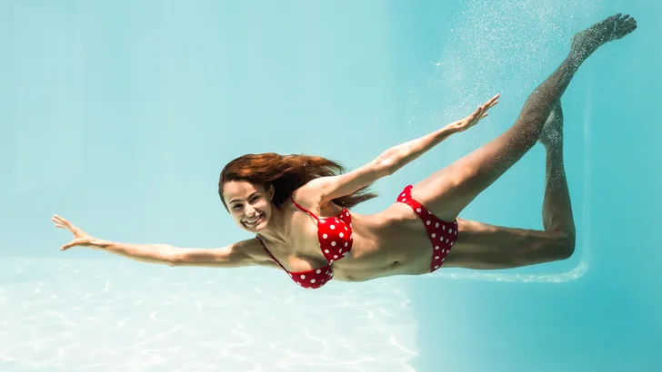 Portrait of smiling young woman swimming underwater