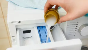 Vrouw doseert vloeibaar wasmiddel voor wasgoed in wasmachine.