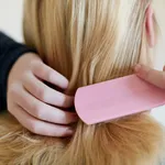 Rearview of young blonde woman brushing hair