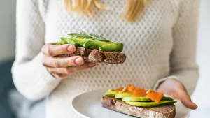Close up of woman holding plate with avocado toast as fresh snack, day light.