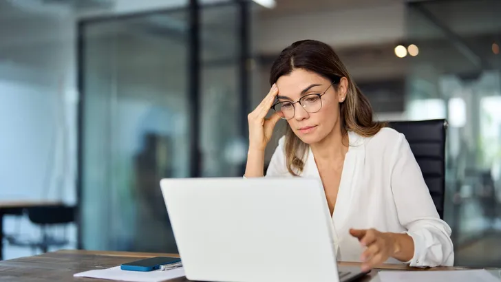 Worried fatigued mature business woman wearing glasses having headache at work.