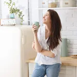 Young happy woman drinking coffee on the kitchen in the morning