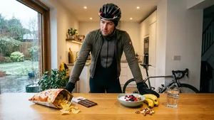 Wielrenner in fietskleding staat in de keuken en twijfelt tussen een zak chips en een gezonde kom kwark met fruit na zijn training.