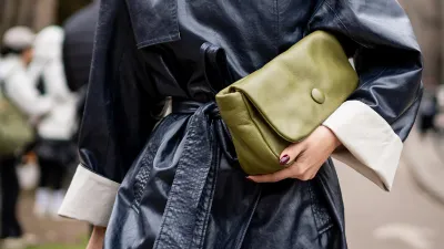 Vrouw met groene clutch onder haar arm, een van de tassentrends voor het najaar van 2026