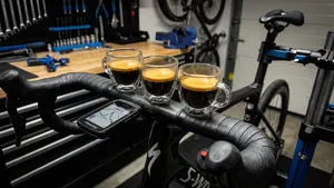 Headerafbeelding van een modern racefiets-stuur, waarbij drie kopjes espresso op een rij op de voorgrond staan. De sfeer is professioneel en prestatiegericht, en de koffie wordt gepresenteerd als brandstof voor de fietstocht.