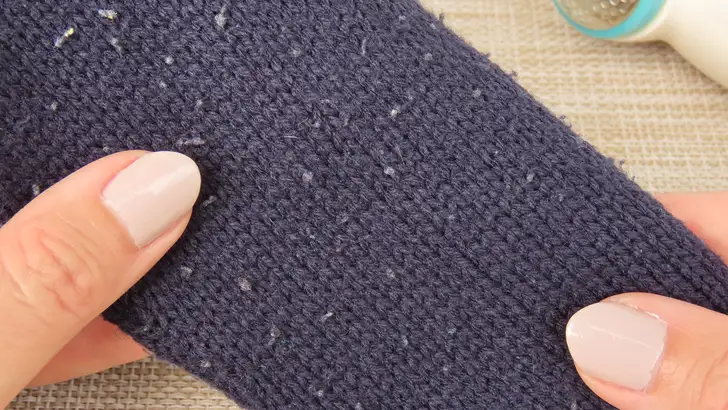 Vrouw houdt trui vast waarvan stof is gaan pillen.