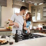 Love, food and cooking with couple in kitchen and hugging for breakfast, morning and happiness. Smile, care and nutrition with man and woman eating at home for happy, health and hungry together