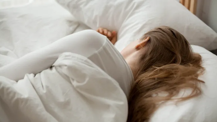 Female sleep on white sheets relaxing in cozy bedroom