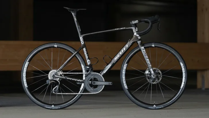 Zijaanzicht van de ultralichte custom SCOTT Addict RC SUB5 racefiets van Dangerholm, met een gewicht van onder de 5 kg, tegen een donkere achtergrond.