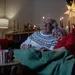 Een ouder echtpaar kijkt tijdens de kerstvakantie een film, zittend op de bank.