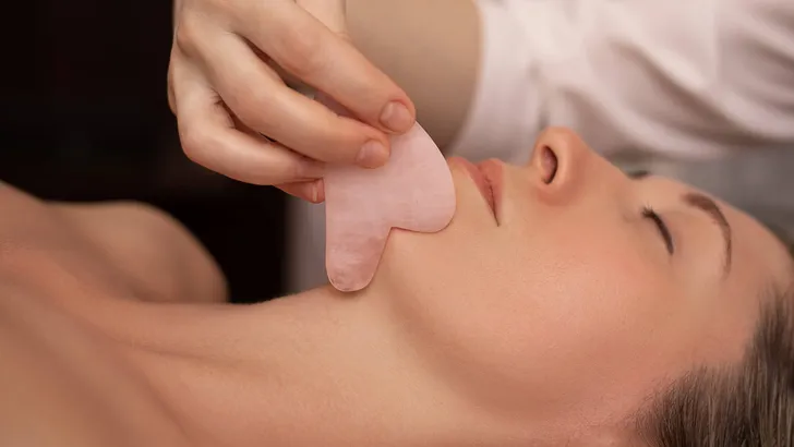 Young and beautiful woman during Chinese traditional massage - Gua Sha. Close-up photo. Beauty treatment in SPA salon