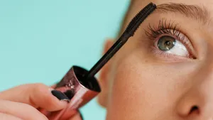 Vrouw doet mascara op en kijkt omhoog.