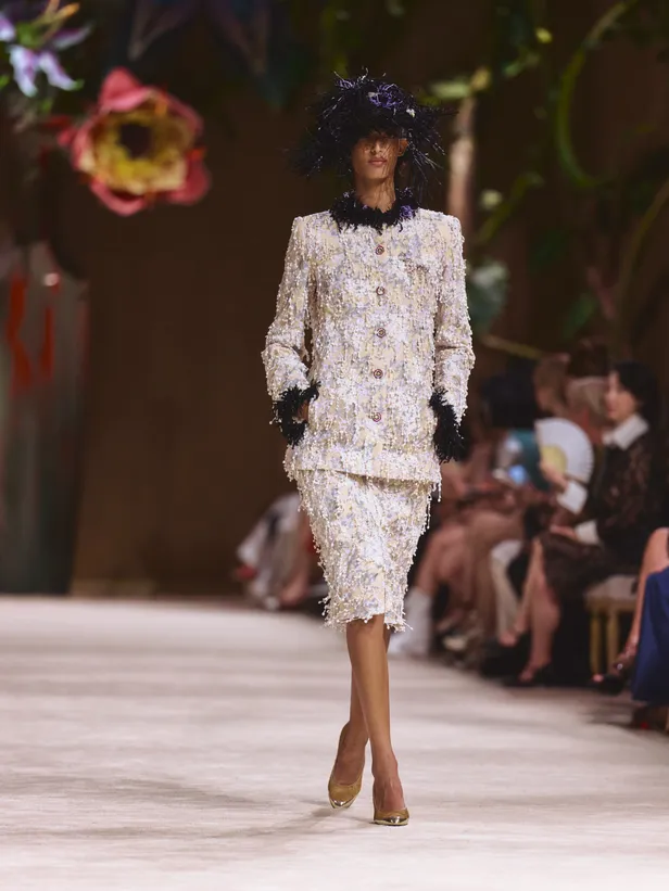 Model in klassiek mantelpakje met donkerblauwe veren tijdens Chanel Haute Couture fashion show in Parijs 2026.