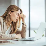 Exhausted businesswoman having a headache in modern office. Matu