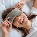 overhead view of happy young woman in eye mask resting in bedroom