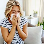 Shot of an attractive young woman feeling ill and blowing her no