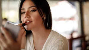 Young woman applying lipstick at a cafe