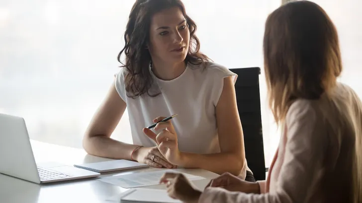 Two diverse serious businesswomen talking working together in office