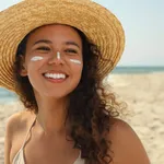 Beautiful African American woman with sun protection cream on fa