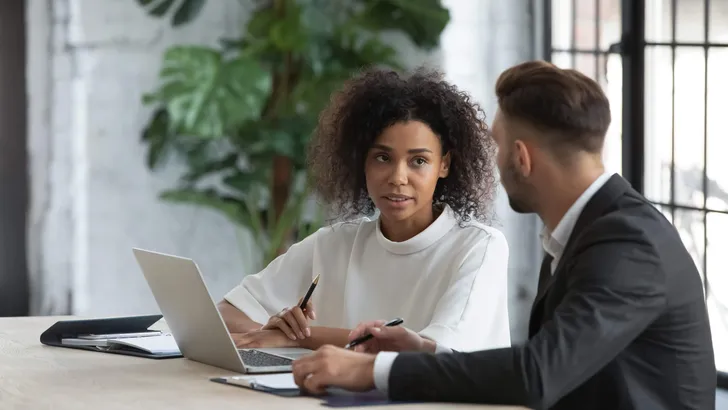 Focused african american businesswoman talking with businessman in boardroom.