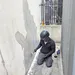 Een gemaskerde man verwijdert de Banksy