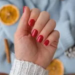 Woman manicured hands, stylish red nails, copy space. Blue sweater Closeup. Winter or autumn style of nail design concept. Beauty treatment