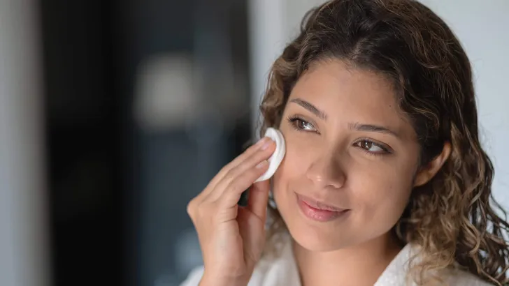 Beautiful woman cleaning her face with a cotton pad