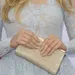 Handen met nude nagels houden een clutch vast