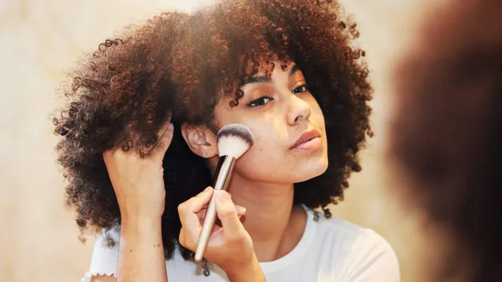 Shot of a beautiful young woman using a makeup brush on her face