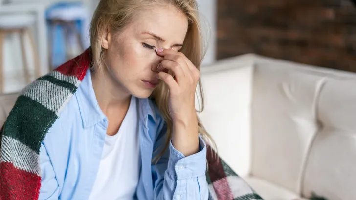 Tired woman with closed eyes touching nose bridge