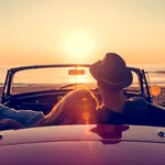 Couple watching the sunset in a convertible car.