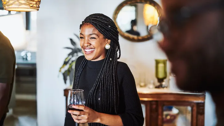 Smiling woman looking away while having wine