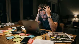 Gestresste wielerfan zit 's avonds laat aan tafel achter een laptop te puzzelen op zijn Tourpool-budget.